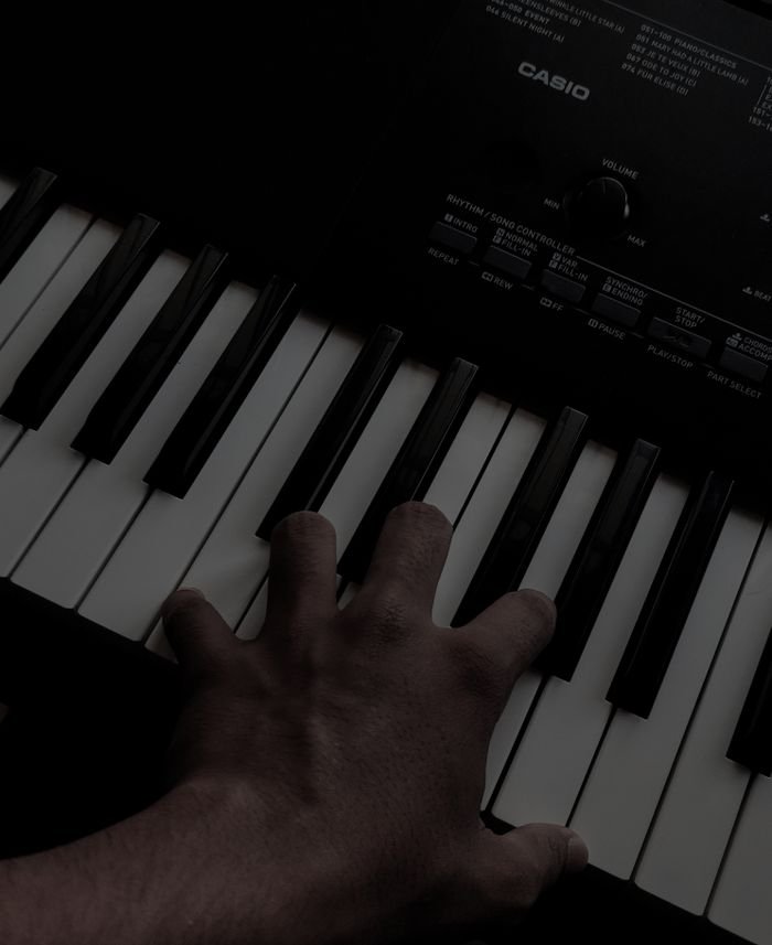 A hand playing keys on an electronic keyboard with visible branding, captured in a close-up shot.
